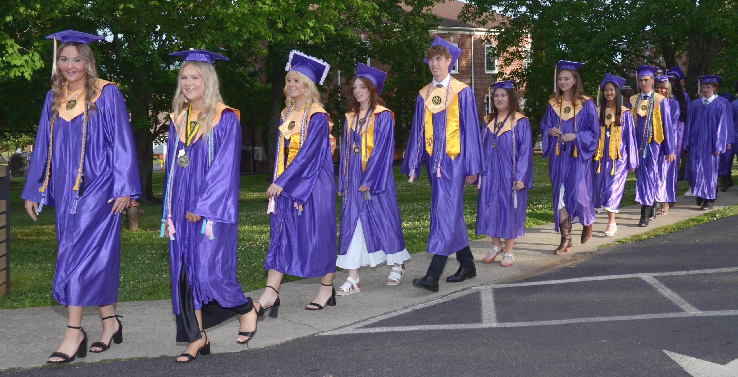 Class of 2026 graduates walking across The King's Academy campus