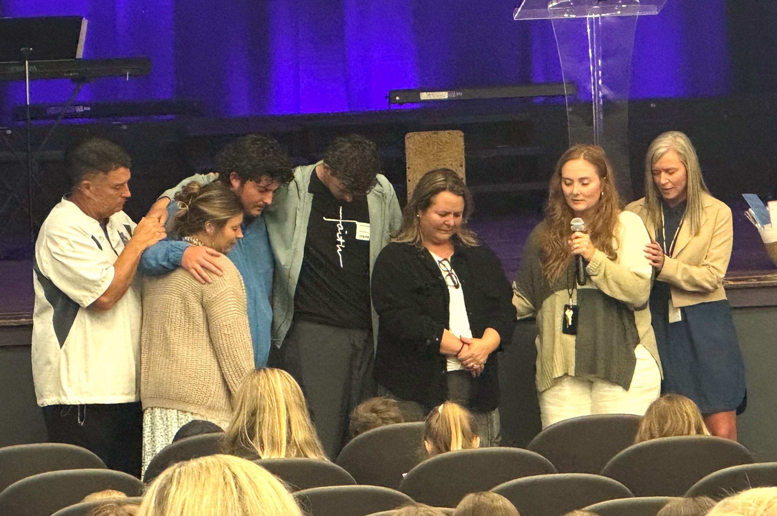 Jennifer Connatser surrounded by her family in prayer during the final elementary chapel service